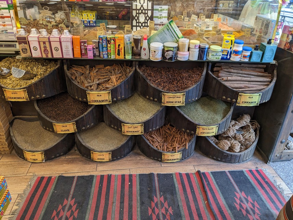 large round trays of raw spices are on display at the entrance to a spice shop