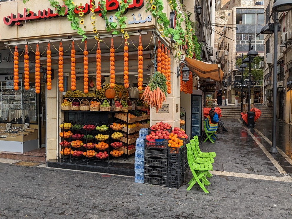 a fresh juice shop on a street corner with bright colorful fruits on display