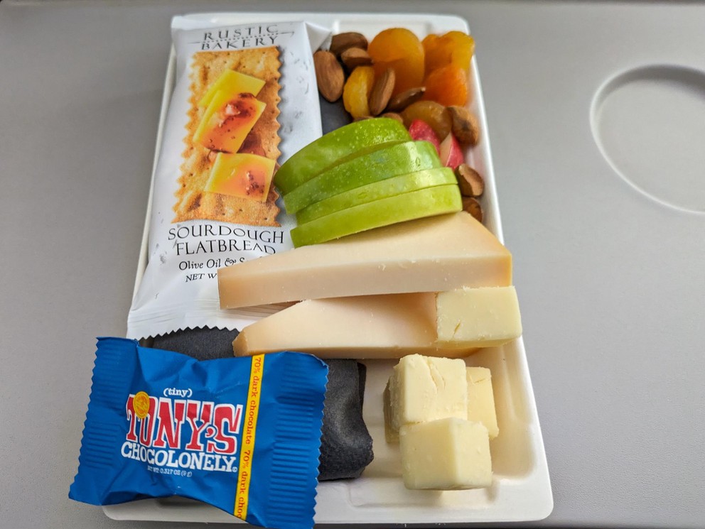 a fruit and cheese plate on an airplane tray