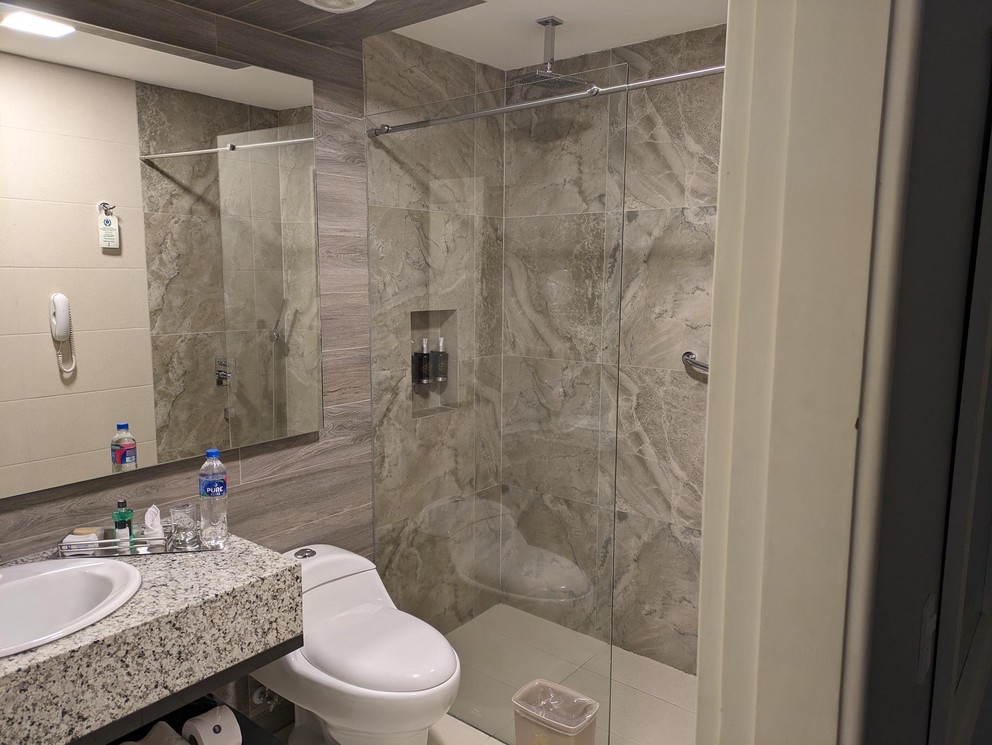 a hotel bathroom with marble walls and glass shower