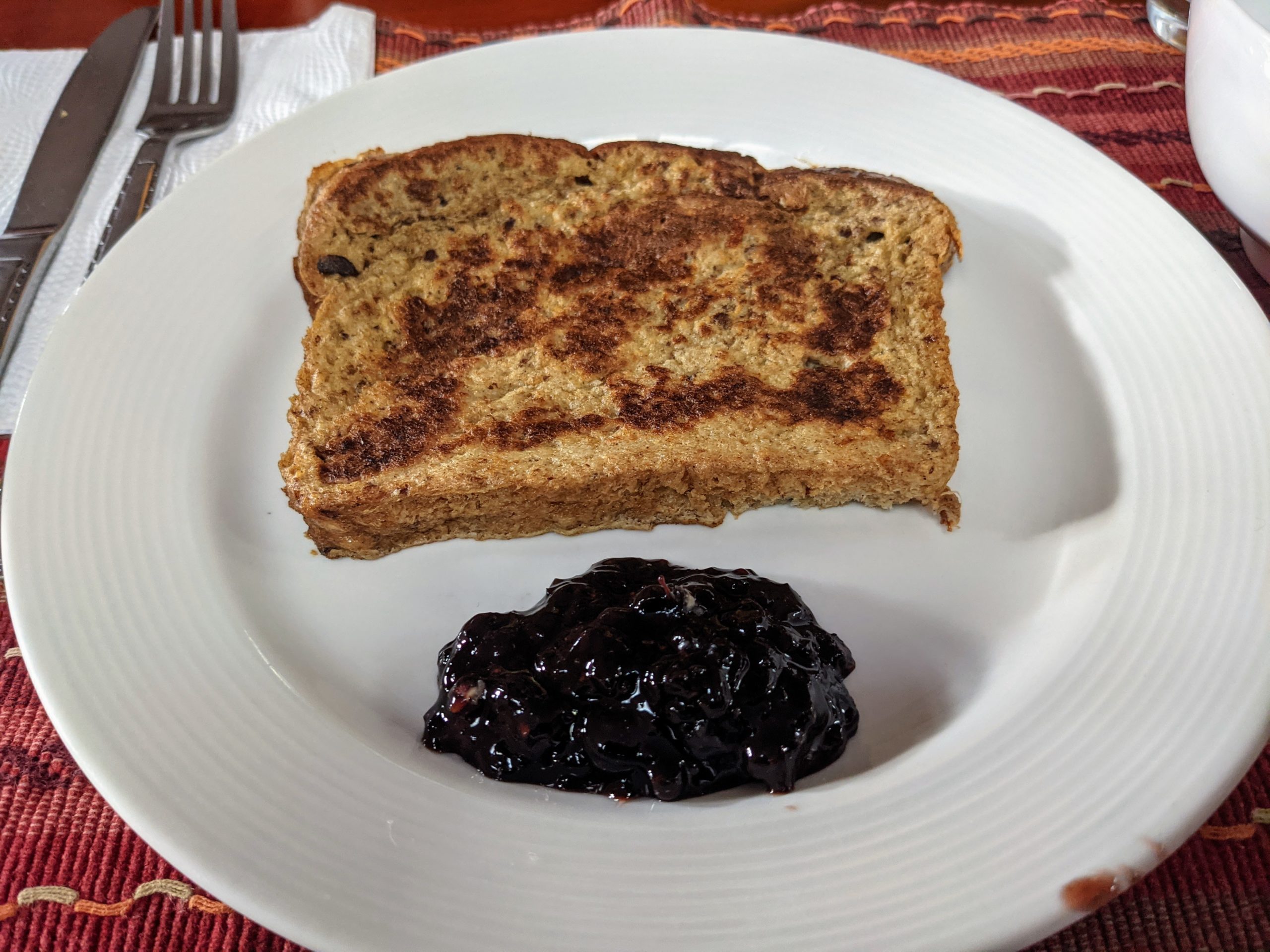 a slice of French toast on a white plate with fig jelly