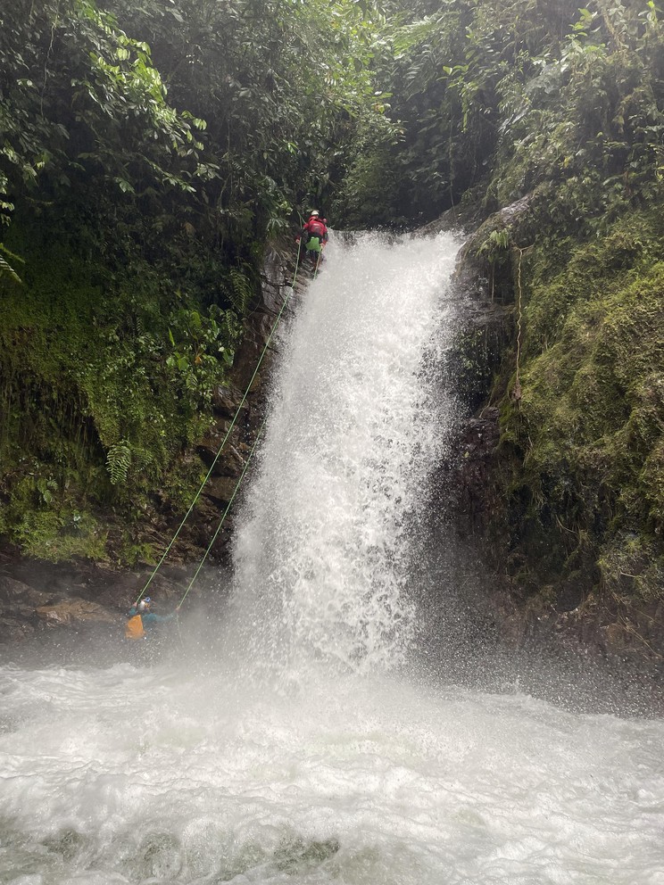 a view of a man rappelling down a fast-moving waterfall