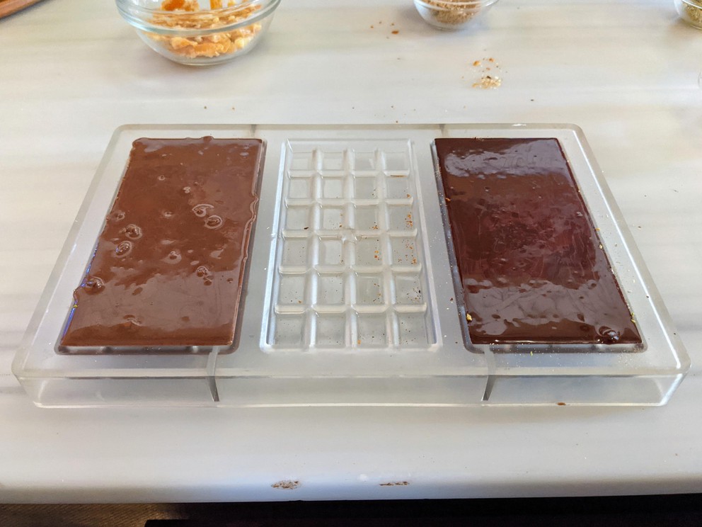 two chocolate bar molds are filled with liquid chocolate and ready to be cooled and finished