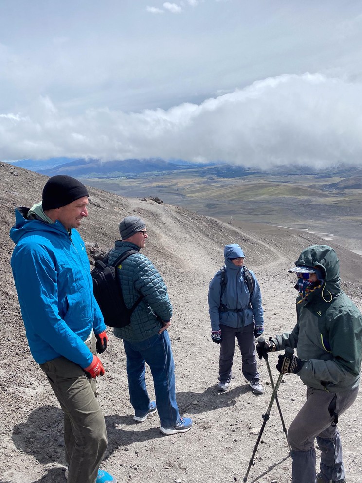 four hikers take a break while ascending a volcano through dirt and ash