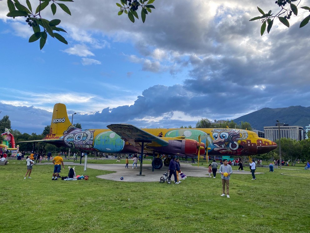 a brightly painted four-engine propeller airplane is a central figure in a family park