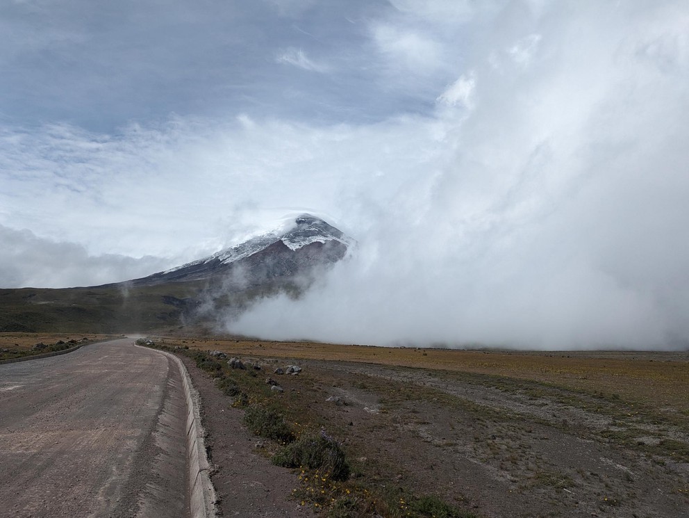 the cone of a volcano is shrouded by flowing clouds