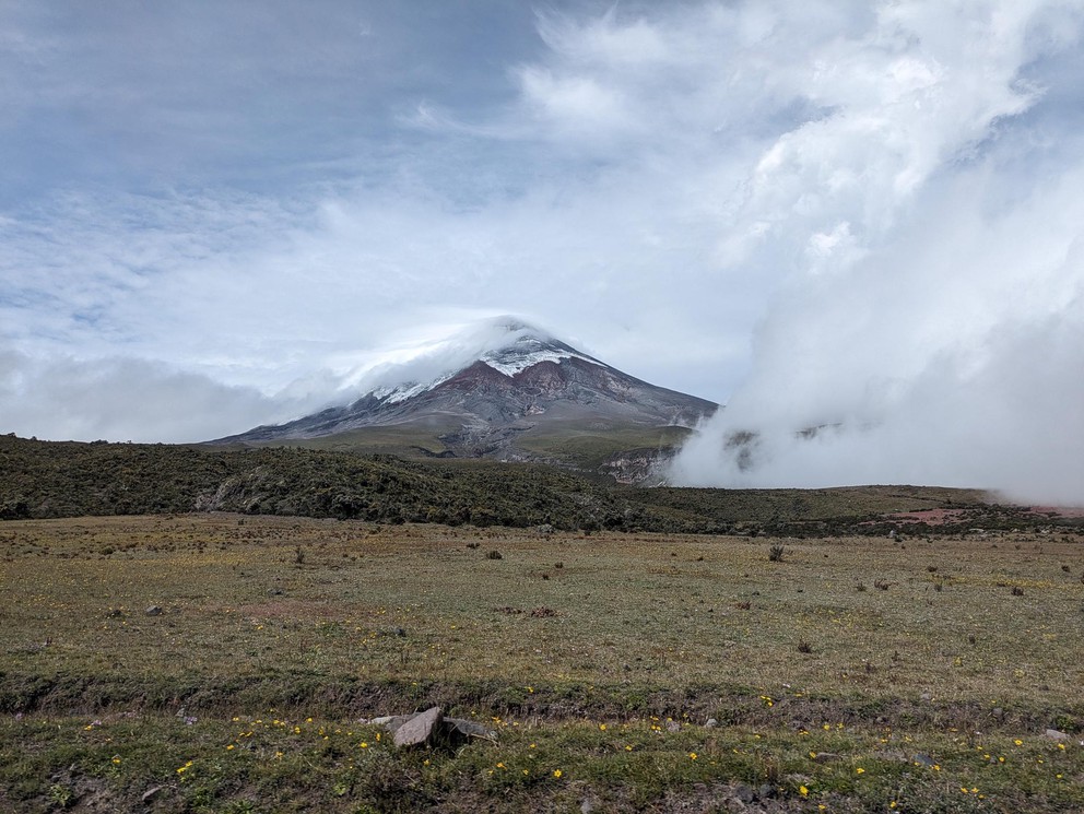 the cone of a volcano peaks through the clouds