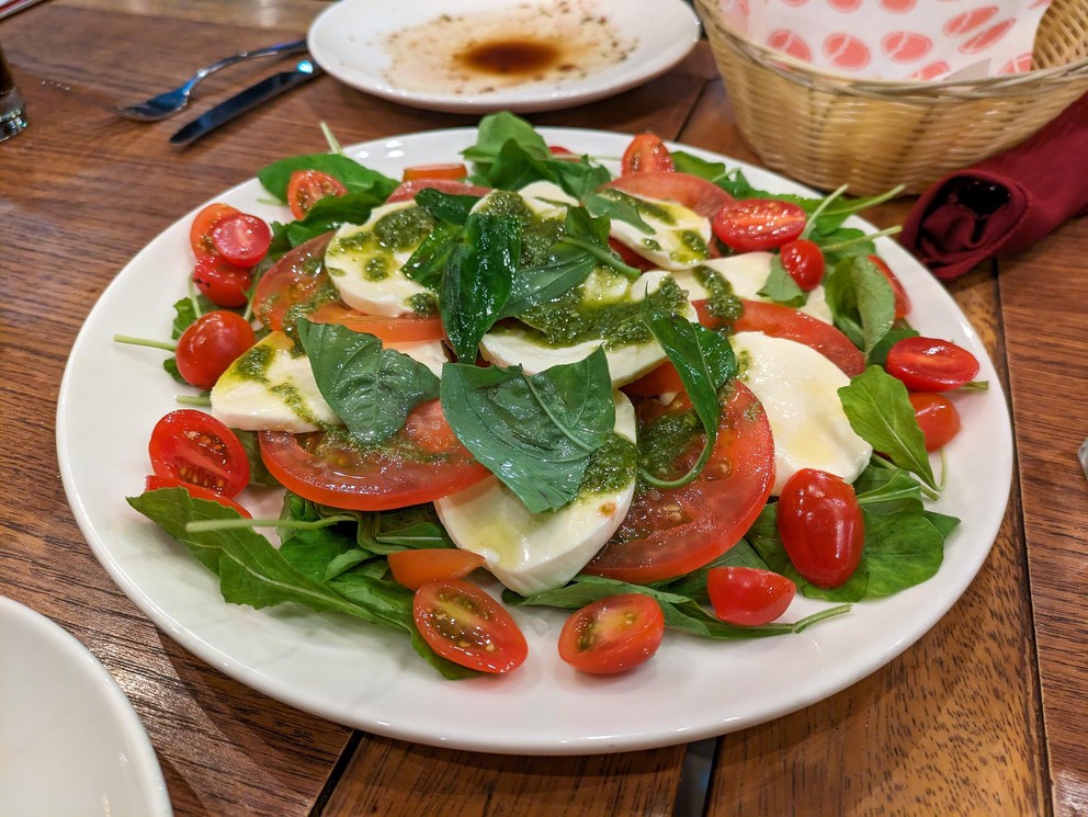 a plate filled with sliced tomatoes, mozarella cheese, and basil