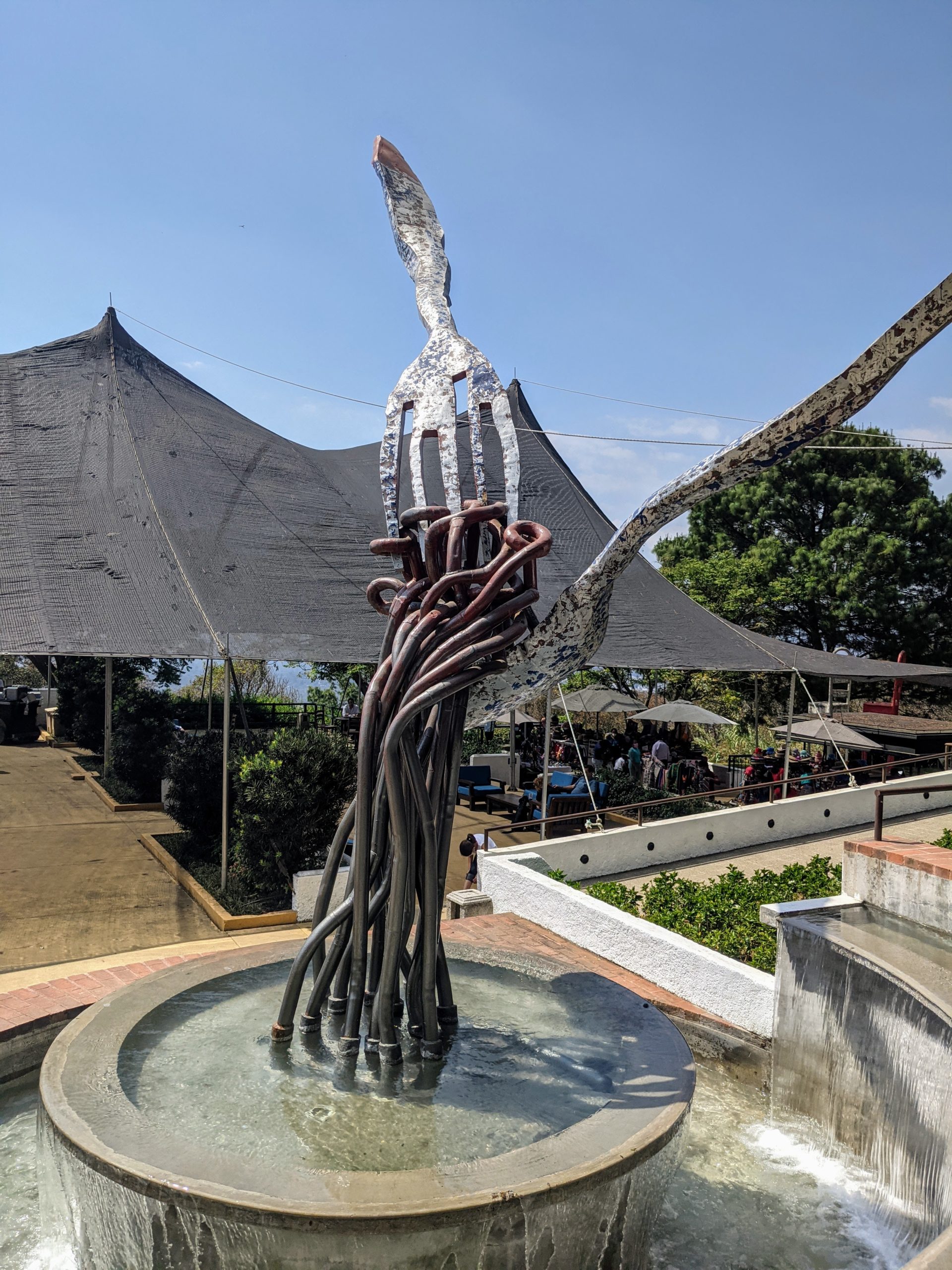 a sculpture of a fork pulling twisted metal pasta noodles out of a bowl and into the air