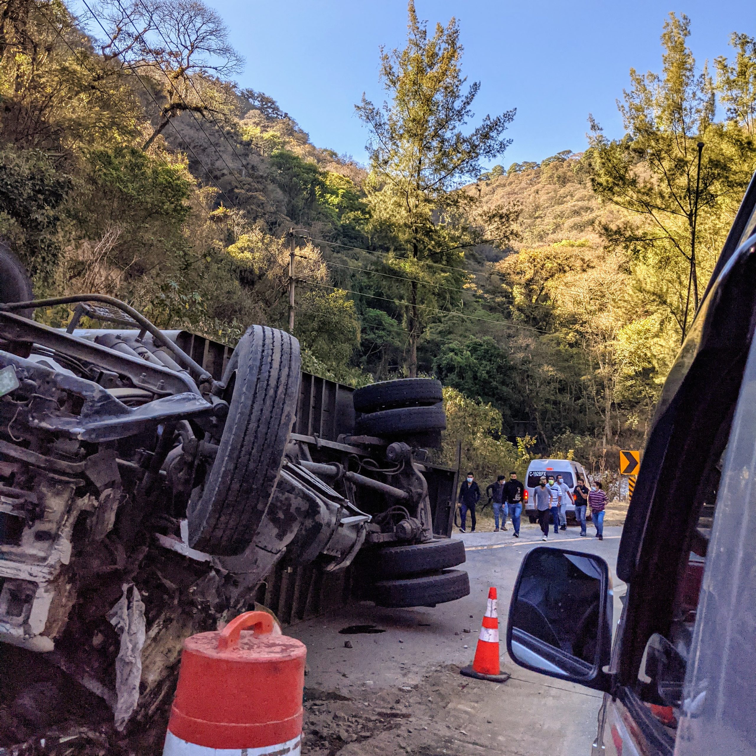 a semi-truck lays upside down facing the wrong way on a one way road