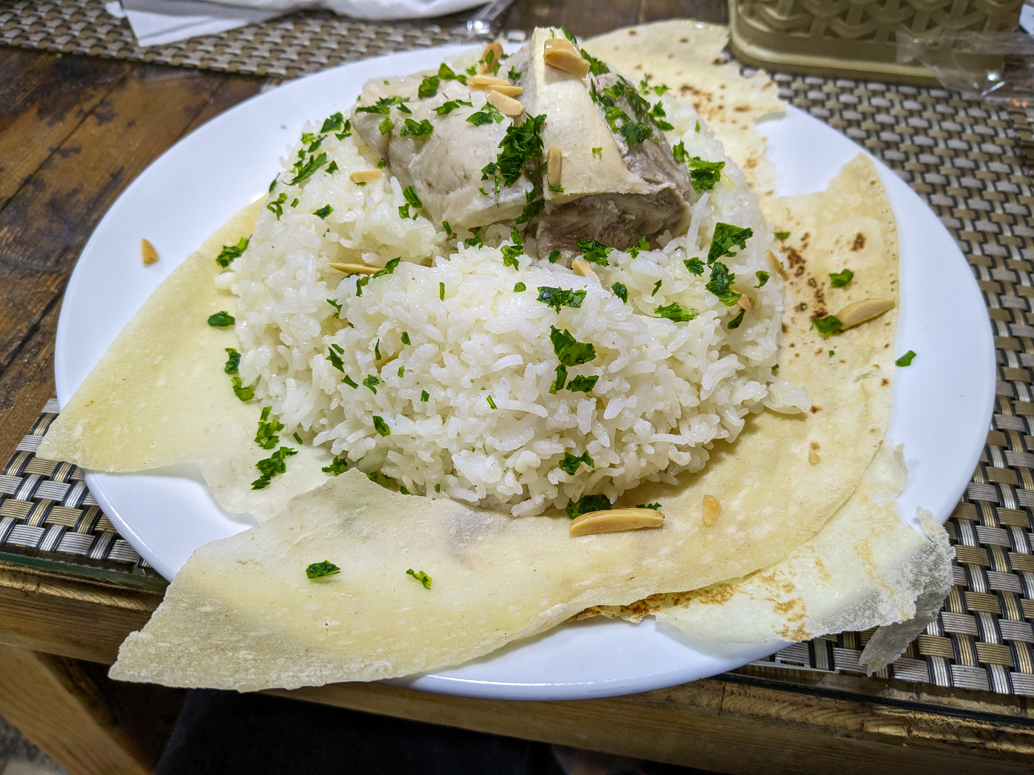 a traditional plate of Jordanian Mansaf with boiled lamb on rice with shrak flatbread and goat yogurt