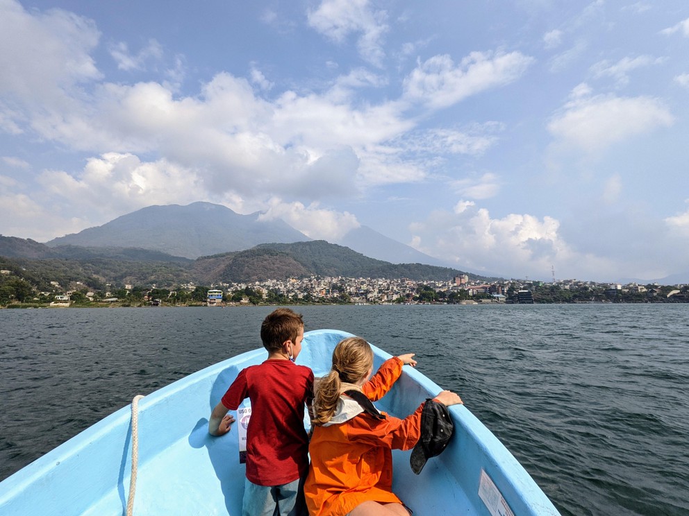two children sit at the front of a small boat as it nears Santiago de Atitlan, Guatemala
