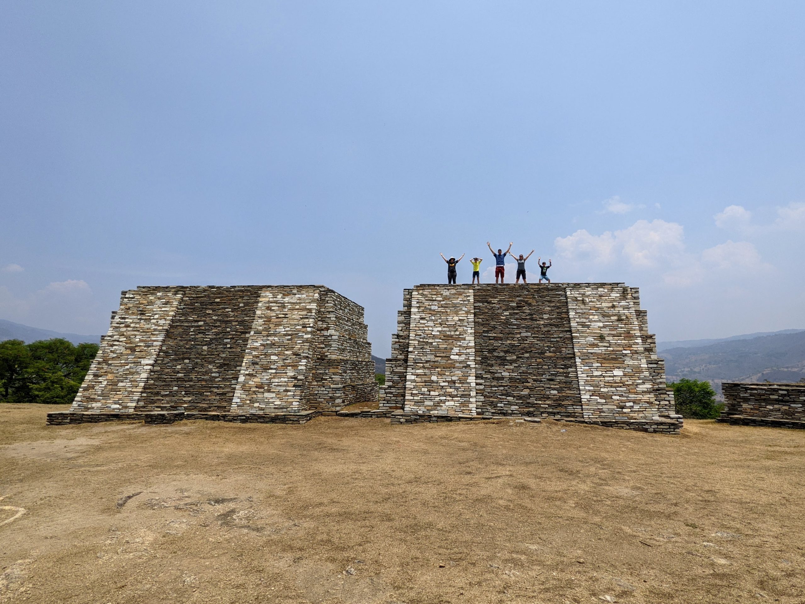 a group of tourists waves from the top of one of the Group B Towers at the Mixco Viejo Mayan Ruins