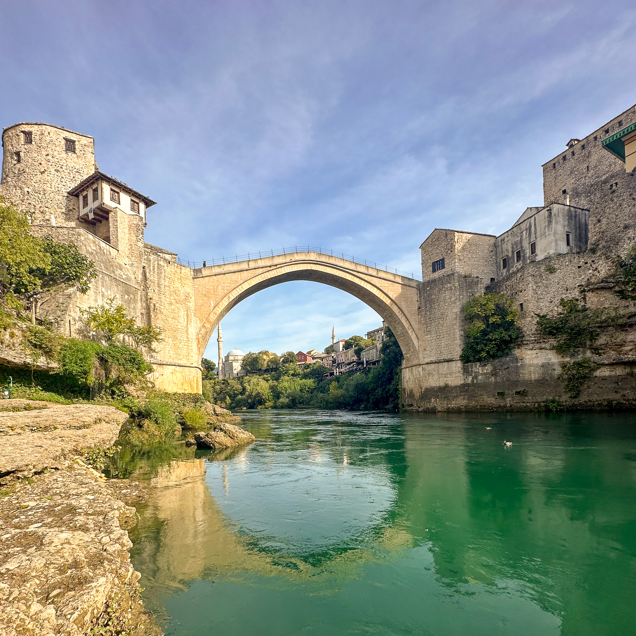 an ancient stone bridge crosses a deep emerald river in Mostar, Bosnia and Herzegovina