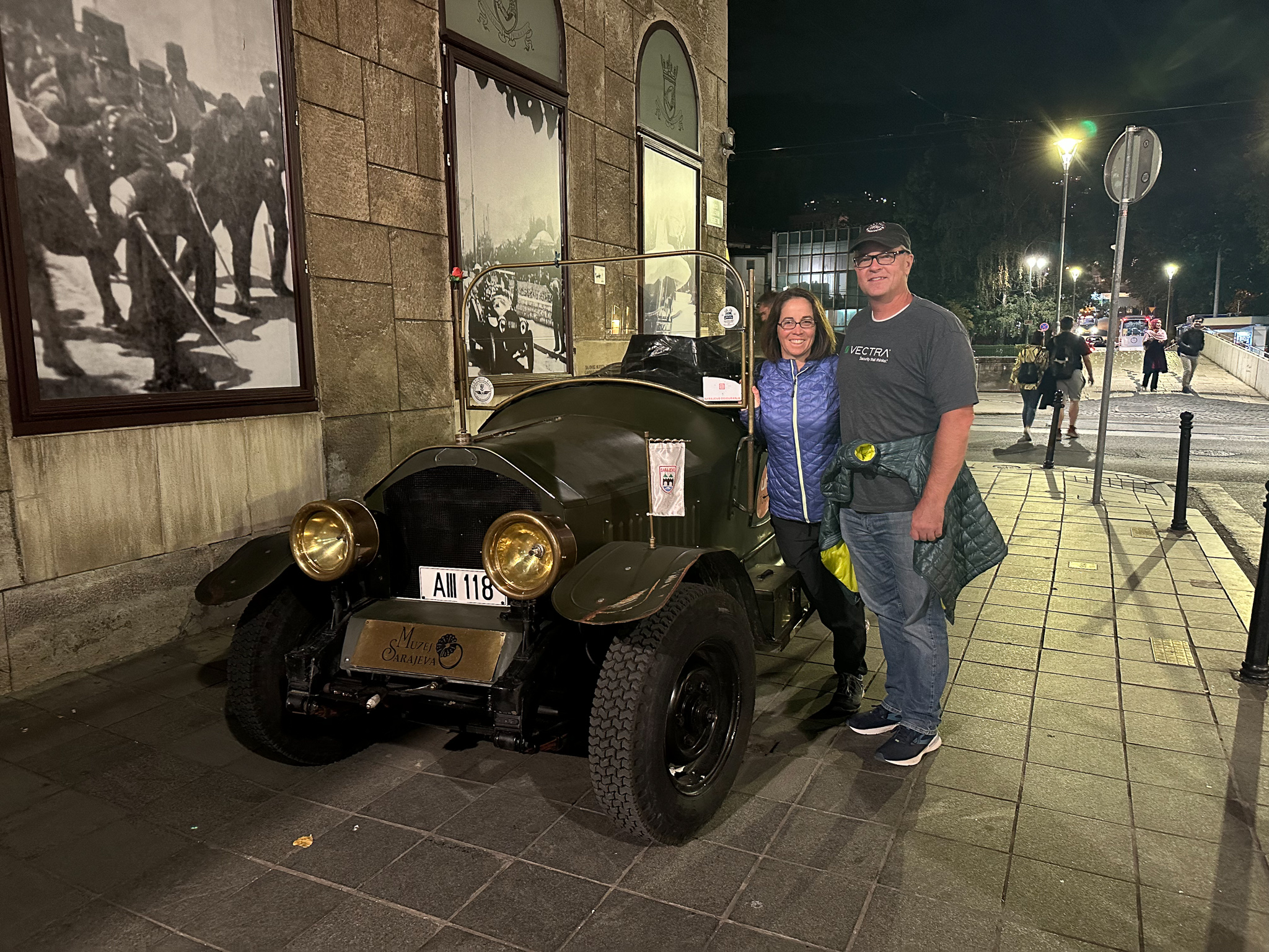 a couple stand next to a replica of the car where Archduke Franz Ferdinand was shot and killed, sparking World War I