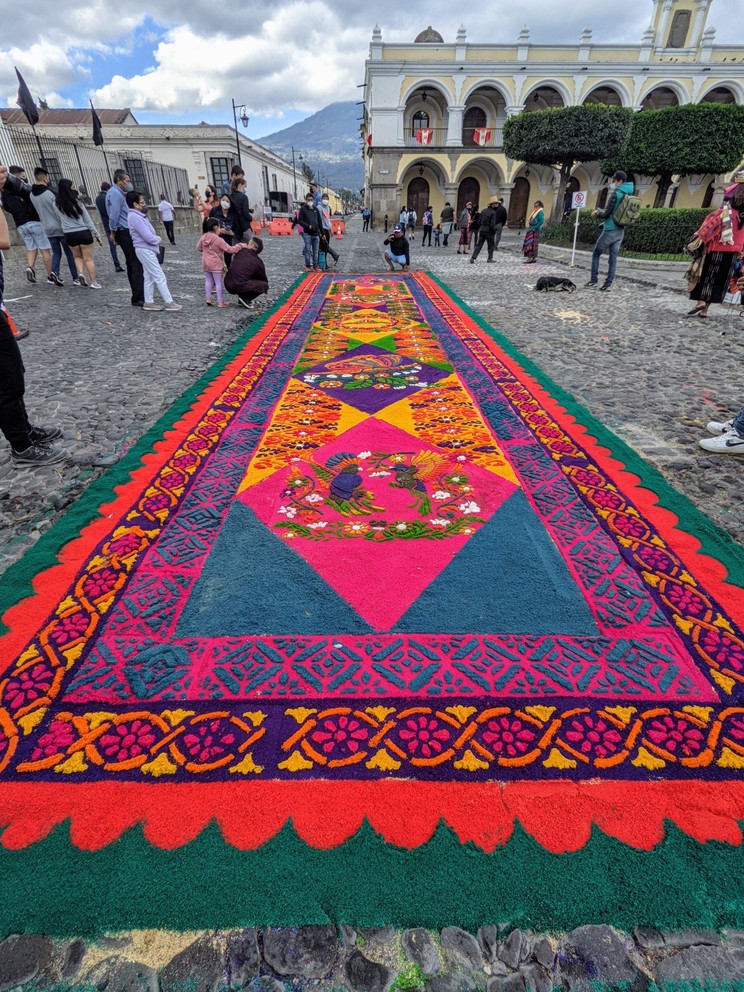 people enjoy a beautiful carpet built for semana santa in the central plaza of Antigua, Guatemala