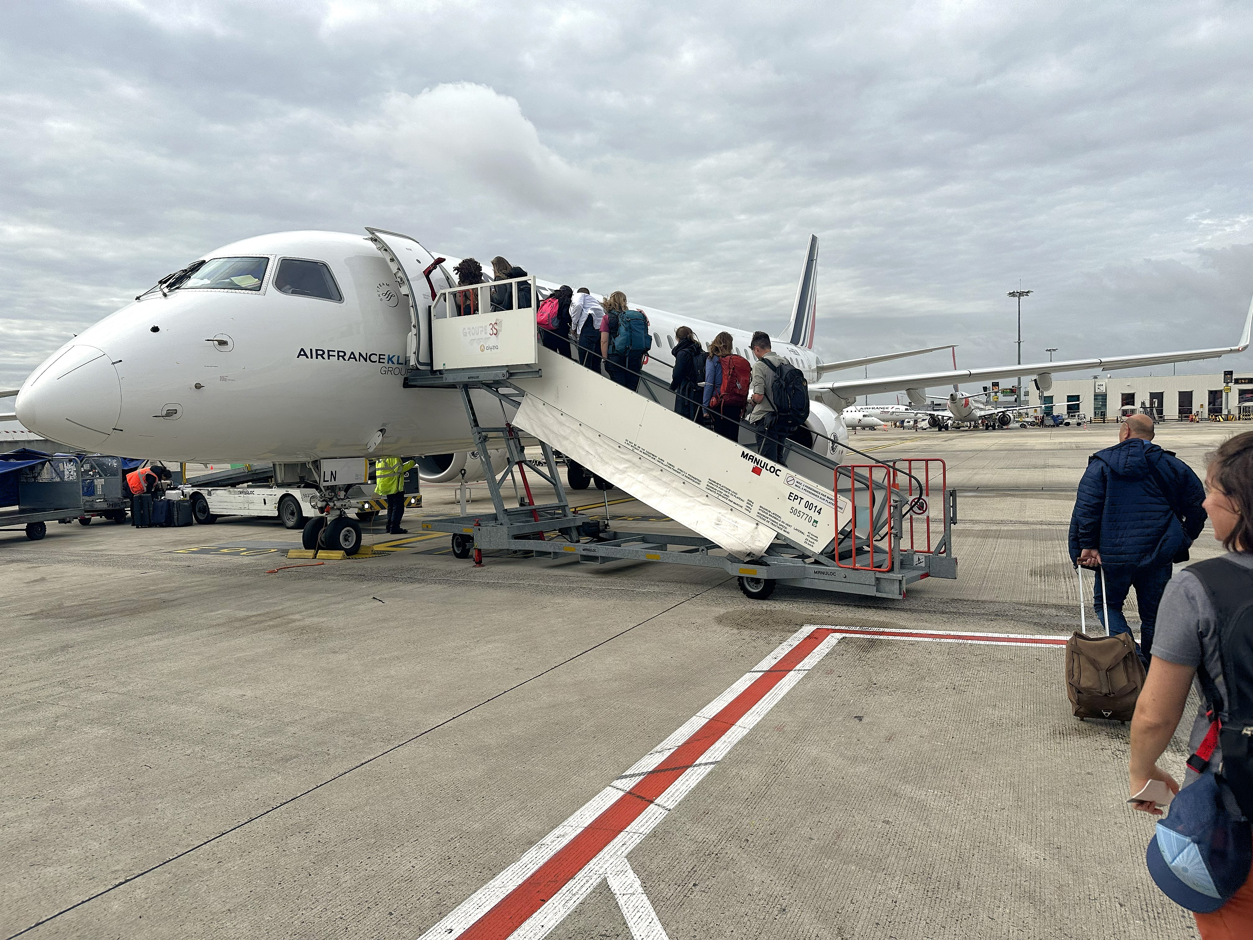 Passengers ascend a mobile jetway to board a small Air France regional jet