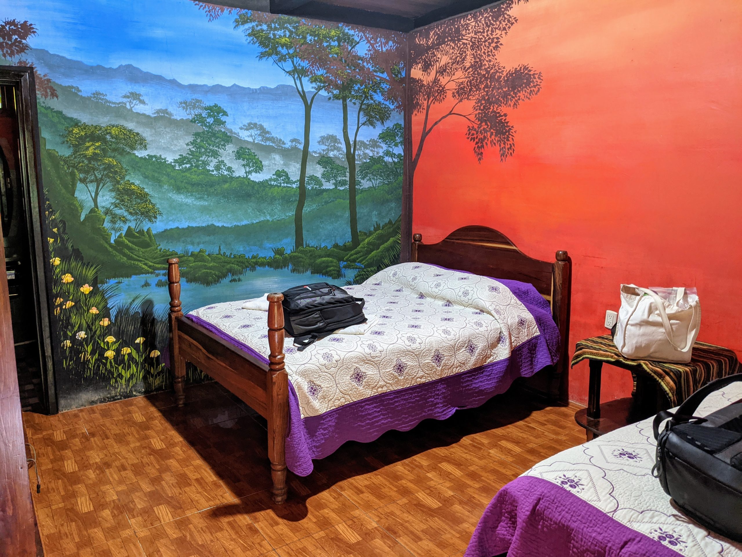 two beds in a hotel room with jungle murals painted on the walls