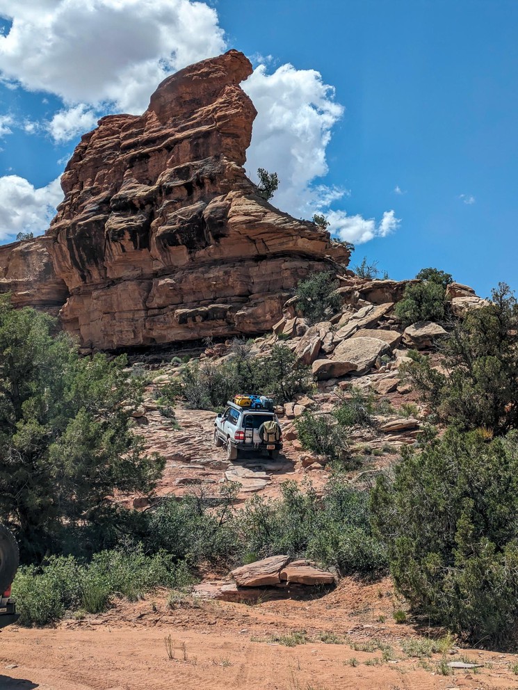 a white Toyota Land Cruiser ascends toward a sandstone fin