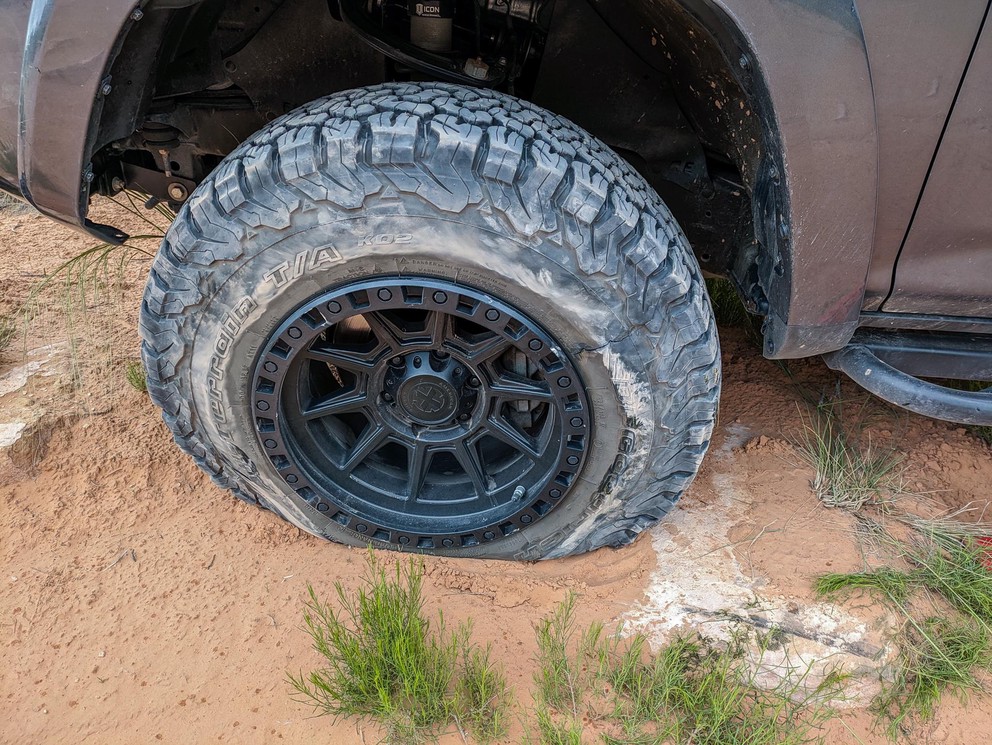 an all-terrain tire is completely deflated in the sand