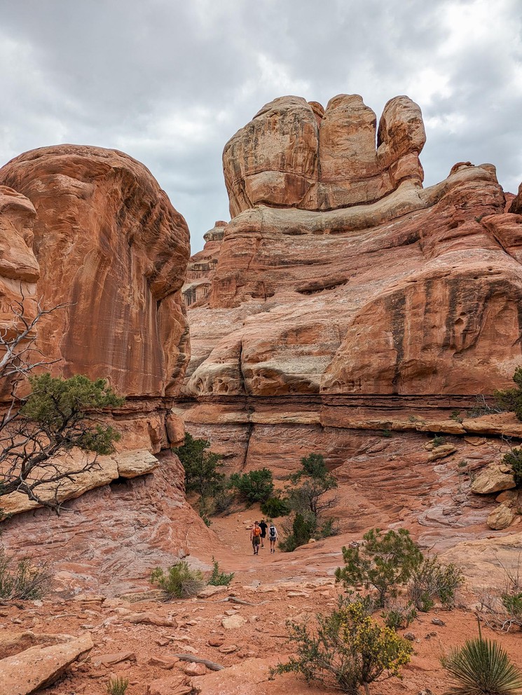 hikers descend between towering sandstone cliffs