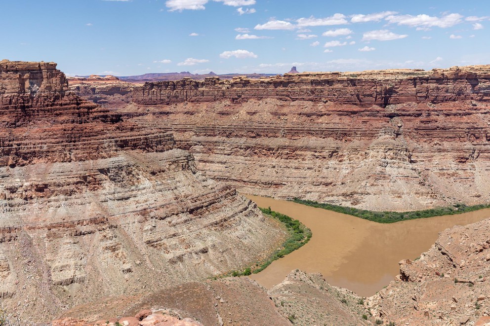two rivers with different shades of water mix together to form a single river at the bottom of a deep sandstone canyon