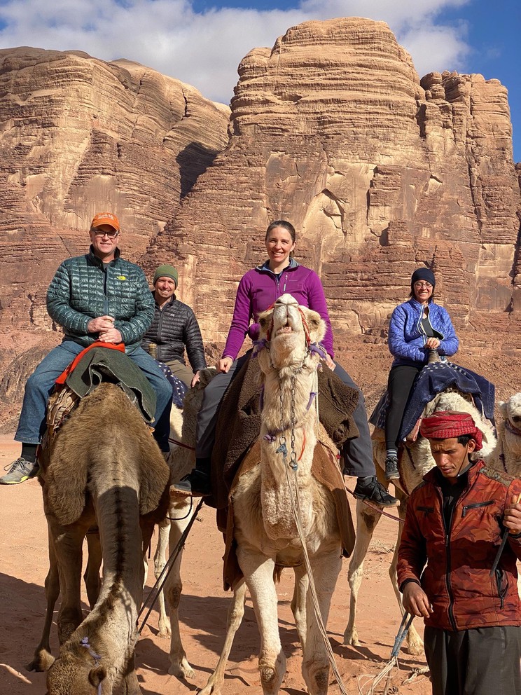 four tourists on camels are led by the owner of the camels through the desert of Wadi Rum
