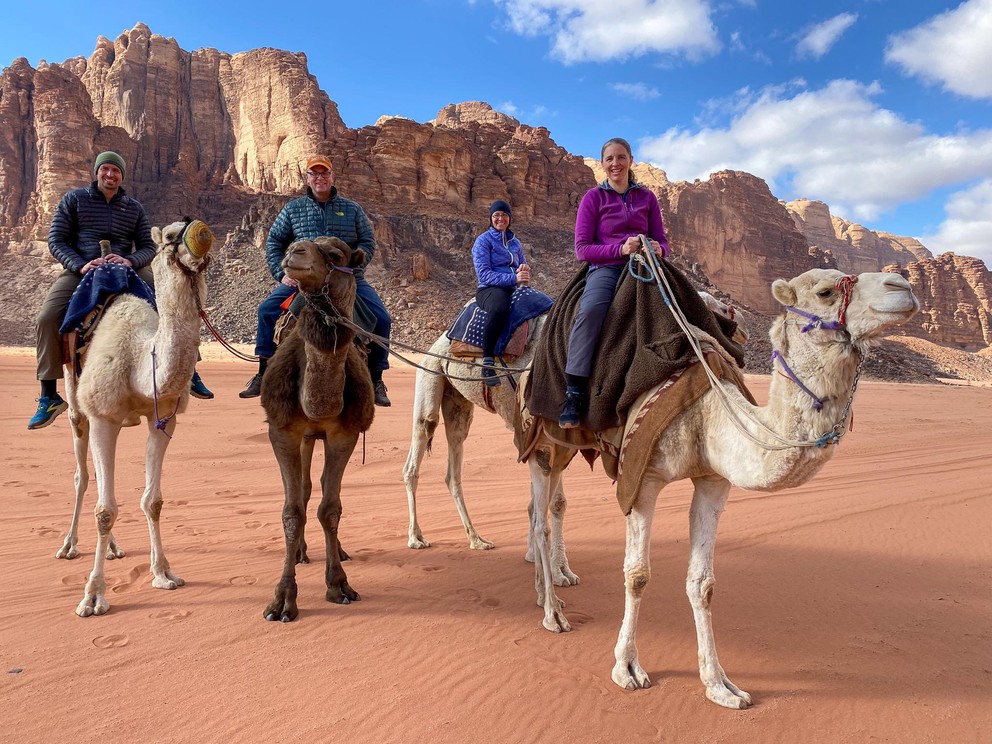 four tourists on camels pose for a photo in Wadi Rum