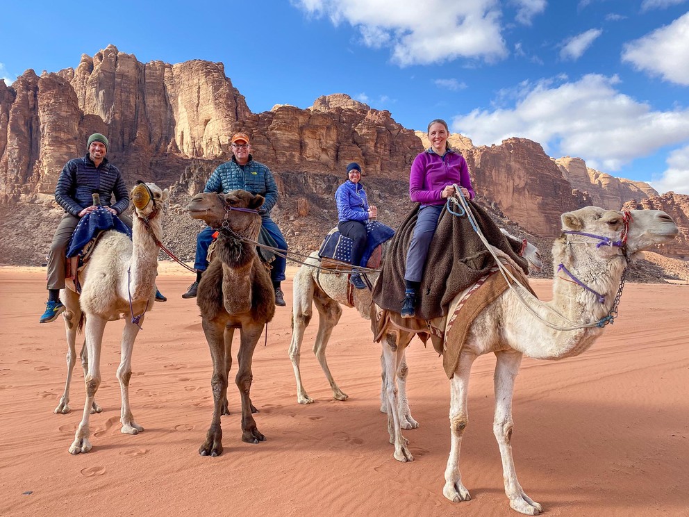 four tourists riding camels stop for a quick photo in Wadi Rum