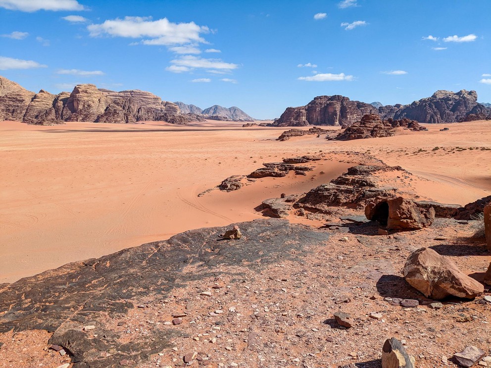 a view deep into a valley devoid of anything other than orange sand and rocky outcroppings