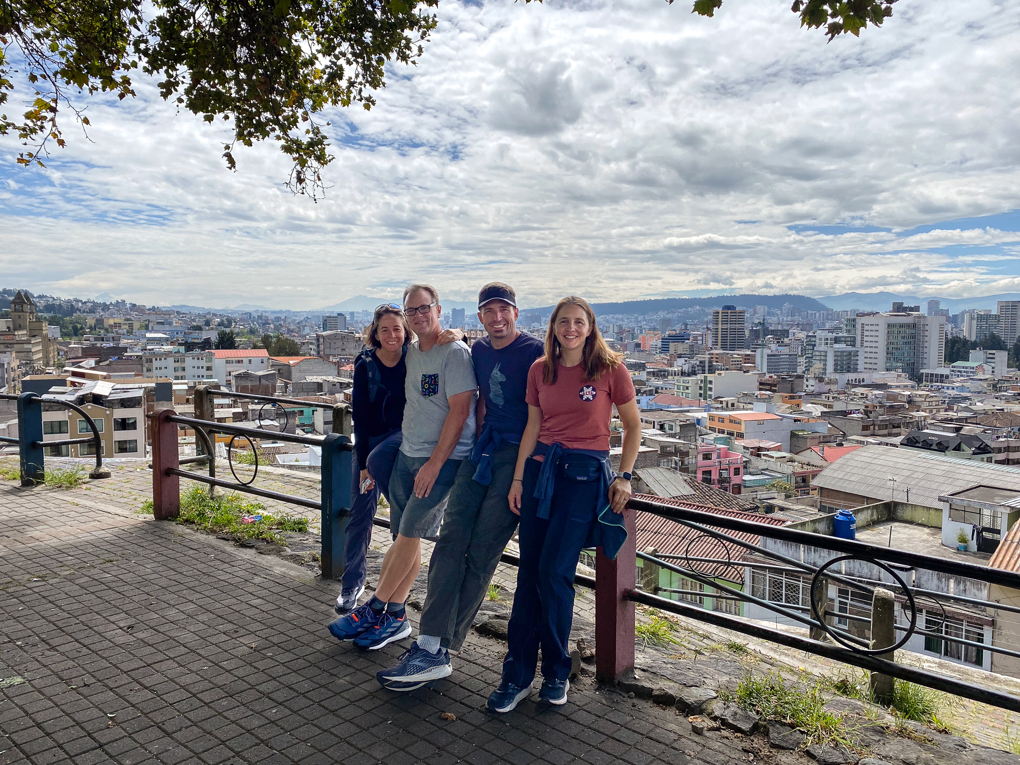 four people stand with their backs against a railing in a park overlooking Quito, Ecuador