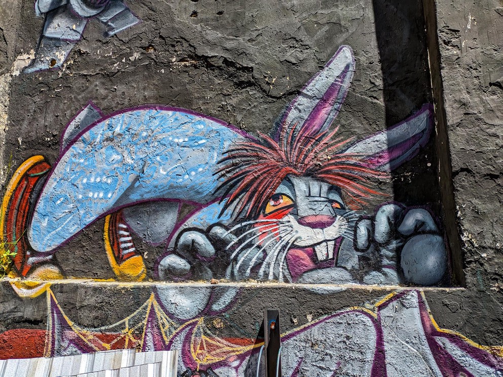 a mural of a rabbit with bloodshot eyes trying to jump up and grab onto a wall