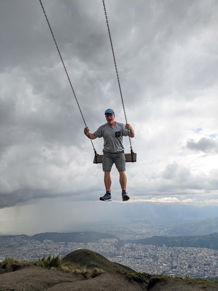a man is excited to swing over the edge of a cliff high above the city