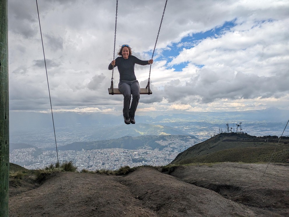 a woman smiles as she swings over the edge of a cliff above the city