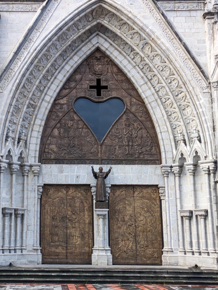 a heart shaped window sits above the two sets of doors at the entrance to the Basilica del Voto Nacional