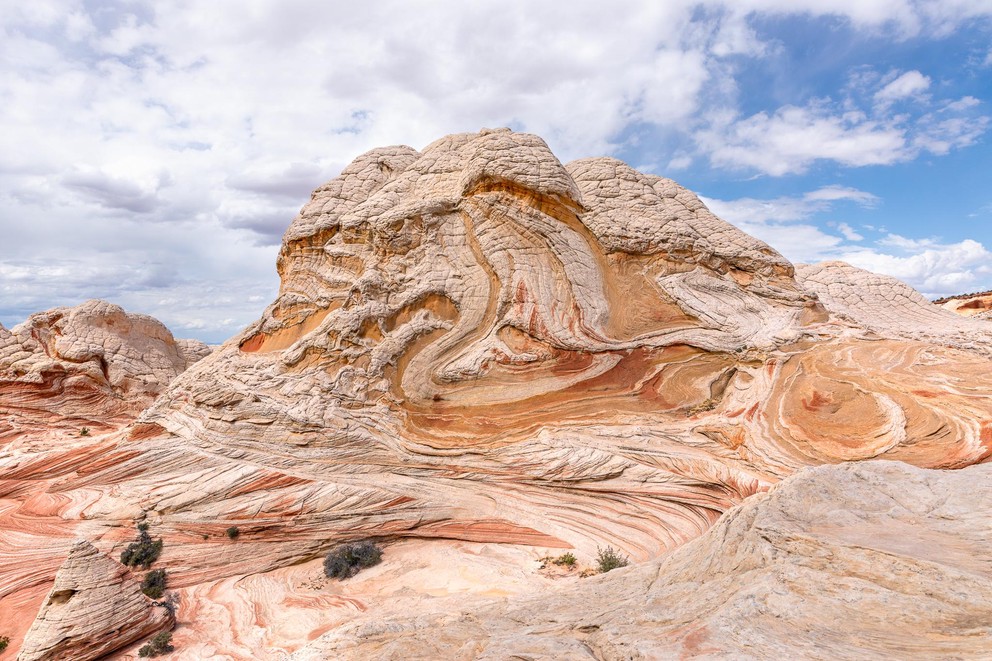 gold and white Navajo sandstone swirls as it rises up above a sea of red and white striped rock