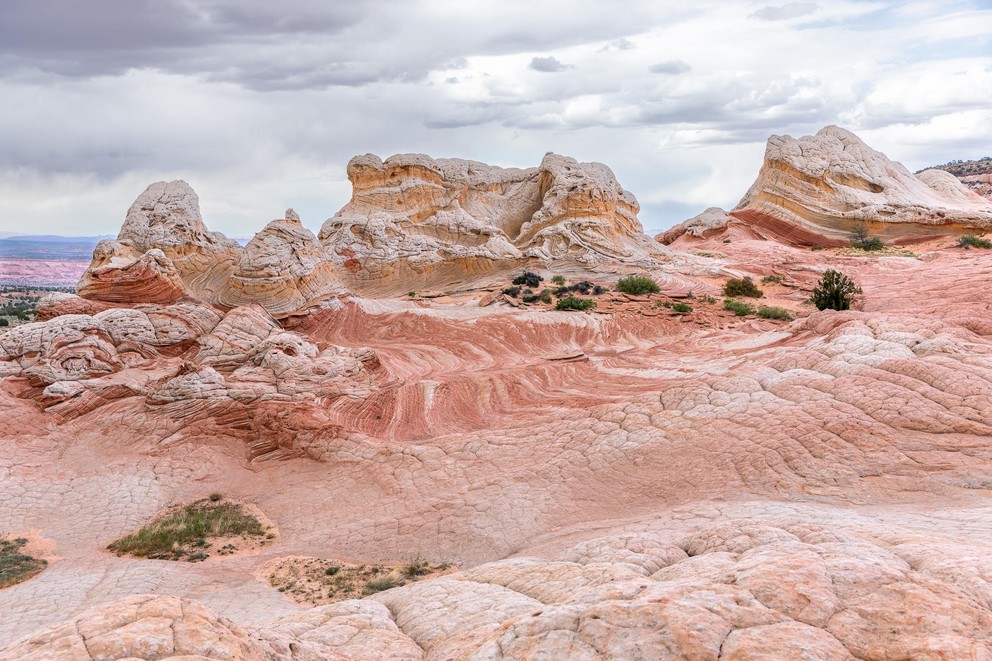 several bursts of yellow and white rock formations pop up from a sea of pink and white sandstone
